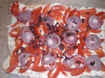 Fordel tomat, rødløg og oliven på pizzabunden.