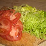 Skær tomater i skiver, og salat i strimler.